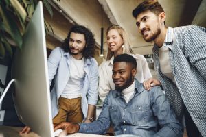 Equipe reunida em frente ao computador checando resultados de treinamentos aplicados com EAD corporativo.